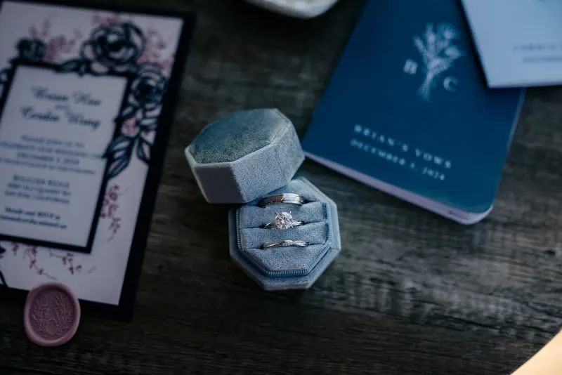 Wedding rings in a velvet box beside the invitation